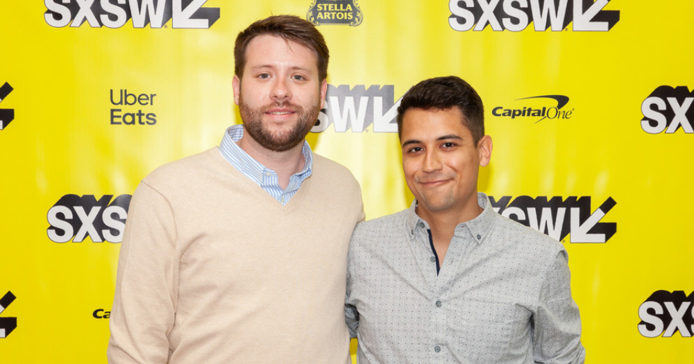 Colby Holt and his husband Sam Probst pose together at their movie premiere with big smiles and and standing close together.