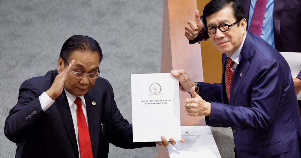 Two lawmakers in Indonesia hold paper representing new criminal code that bans sex outside of marriage.