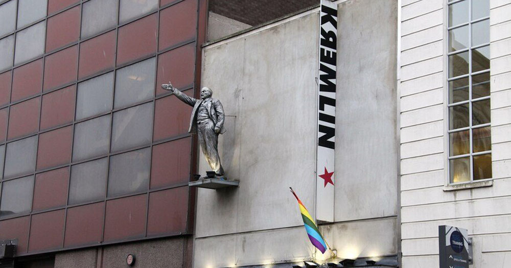 The photograph shows the front of the Kremlin queer club in Belfast. Above the doorway is a statue of Lenin with his arm raised in a communist salute.