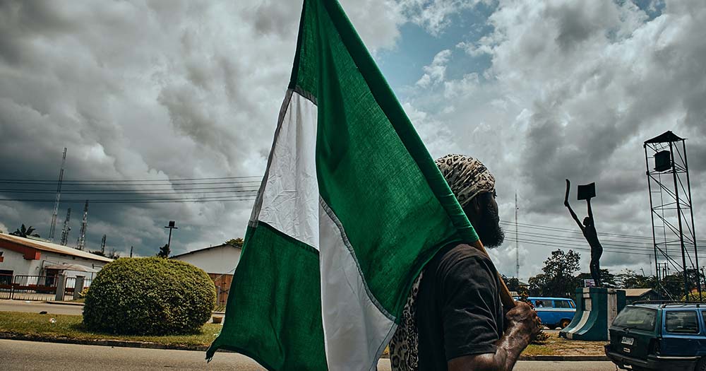 Man carrying green and white Nigerian flag, earlier this week, guests were arrested during a gay wedding in Nigeria.