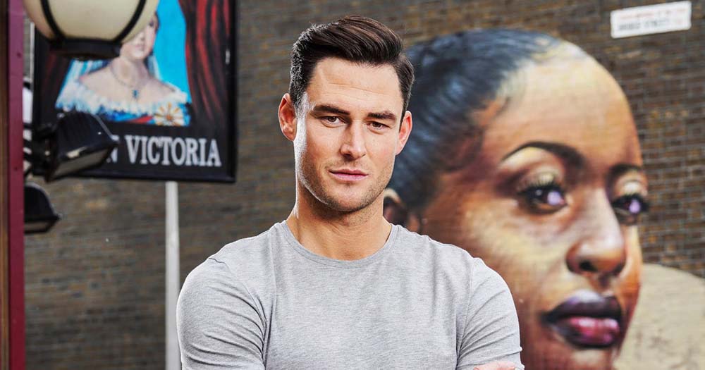 EastEnders actor, James Farrar, poses in a gray tshirt, his character is HIV positive.