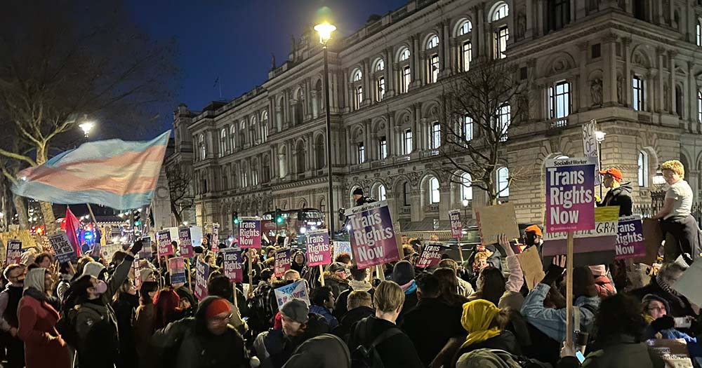 A crowd of hundreds holding signs in support of trans rights protest the UK government blocking the gender recognition bill.