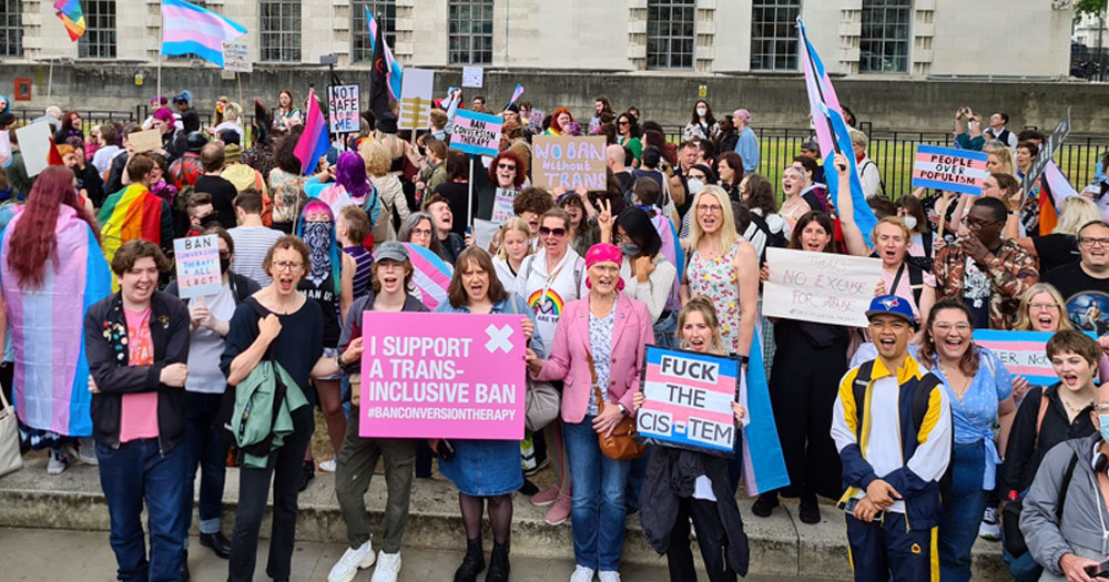 Protest in the UK about a conversion therapy ban, with people holding signs of support and waving trans flags.
