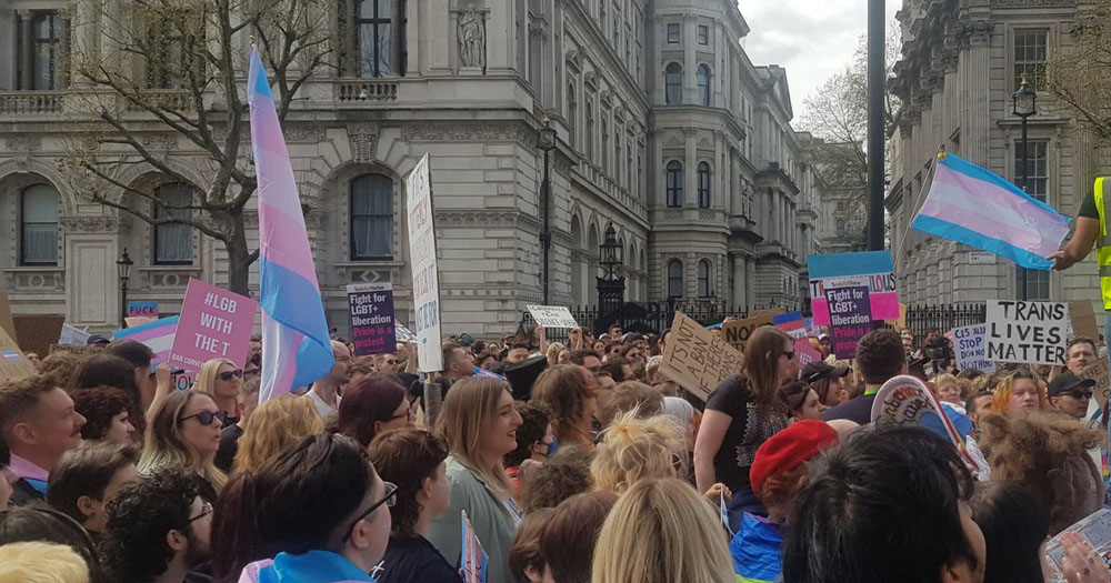 The image shows demonstrators at a rally against restrictions on trans rights in the UK.