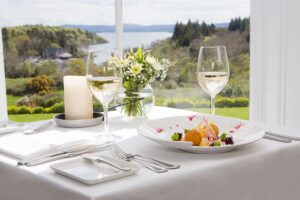 An image of a dining table with a plate of food and a glass of wine in the restaurant at the Lodge at Ashford Castle. 