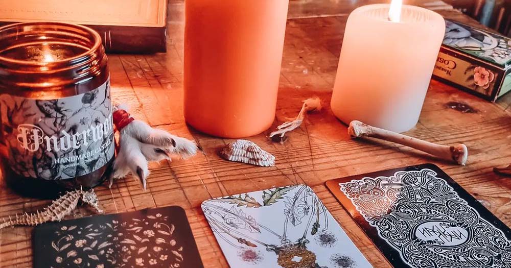 A spread of black tarot cards and candles representing how a growing number of queer people are practicing witchcraft.