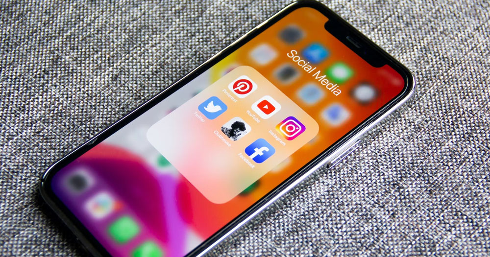 This article is about anti-LGBTQ+ ads on TikTok, Facebook and YouTube. In the photo, a phone showing several social media apps on the screen.