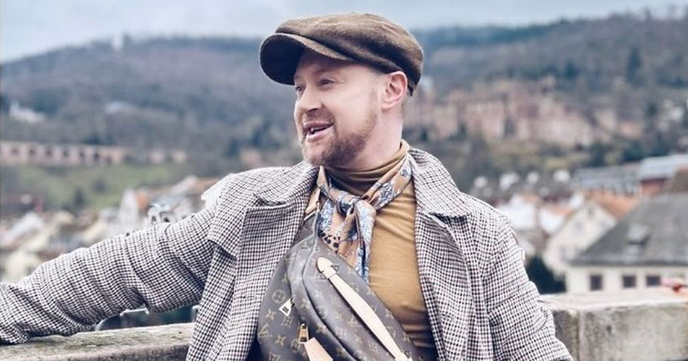 Gay influencer David Babington, who was victim of an attack in Cork City, posing in front of a landscape.