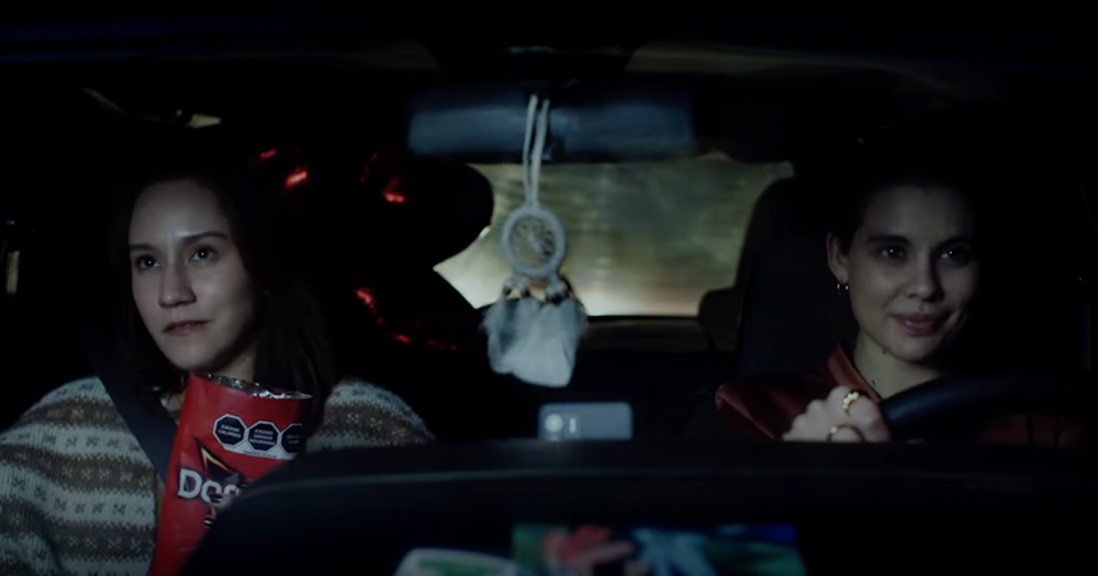 Two lesbian women sit in the front seat of a car enjoying a bag of Doritos in this ad.