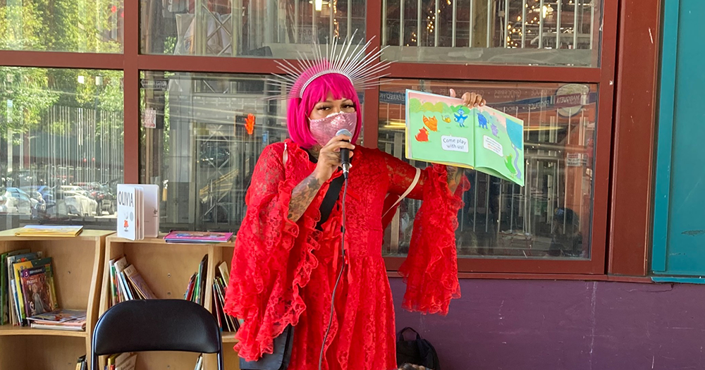 Drag performer wearing red costume reading to during a drag story hour as Tennessee becomes first US state to legally ban drag shows