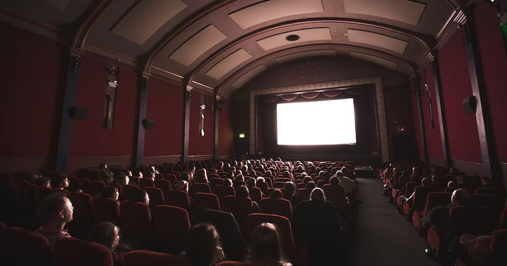 This article is about the first LGBTQ+ film festival in Ukraine. In the photo, a cinema with people sitting and looking at a white screen.