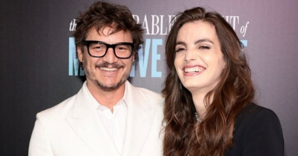 Pedro Pascal wearing glasses and a white suit poses with his beautiful trans sister, Lux.