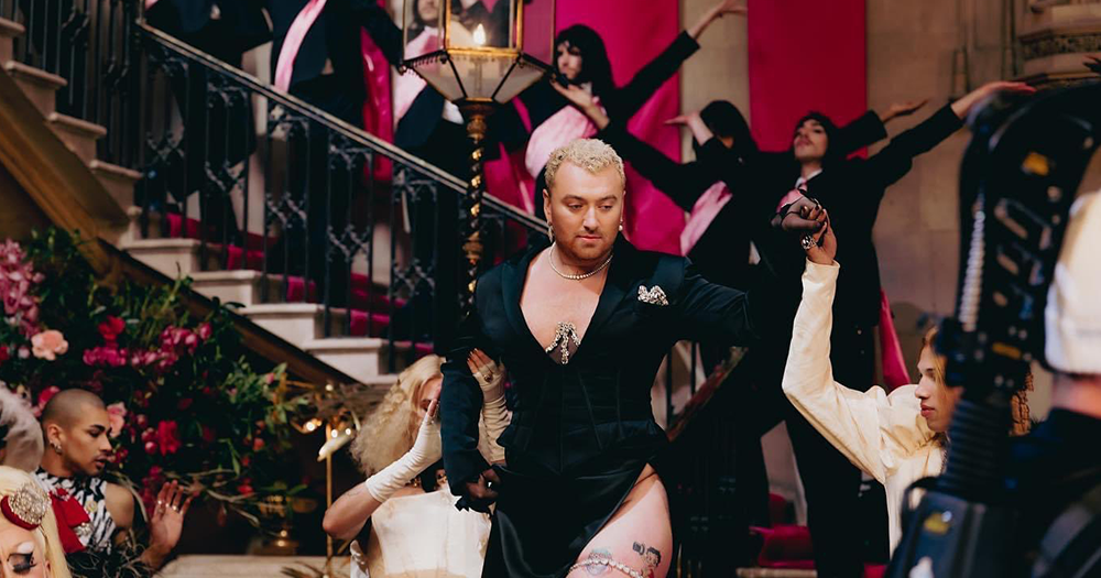 Sam Smith wearing a black dress surrounding by dancers in their music video which received backlash for celebrating their queer identity, body, and sexuality.