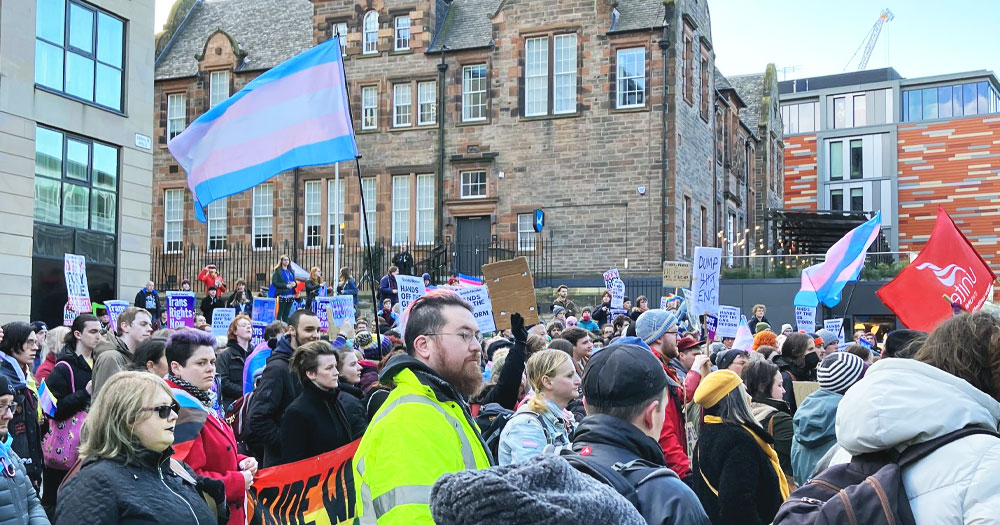 This article is about Welsh reforms for gender recognition that could be blocked by the UK government. In the photo, a protest for trans rights with people waving trans flags and carrying signs.