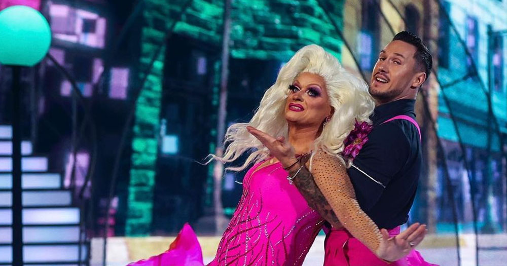 Photo of Panti and Denys Samson on Dancing with the Stars, performing a dance with Denys holding Panti, who is wearing a bright pink dress.