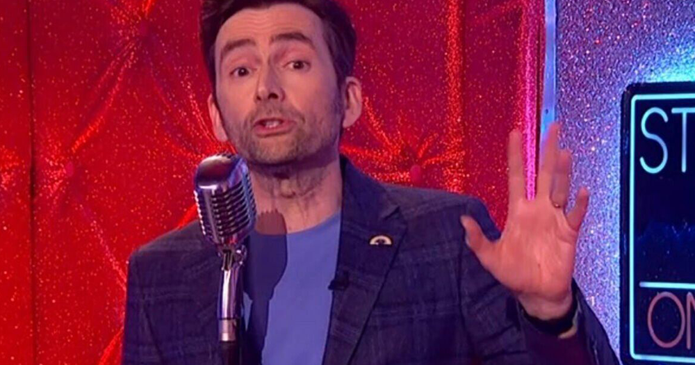 David Tennant wears suit with non-binary pride badge pinned on his jacket.  