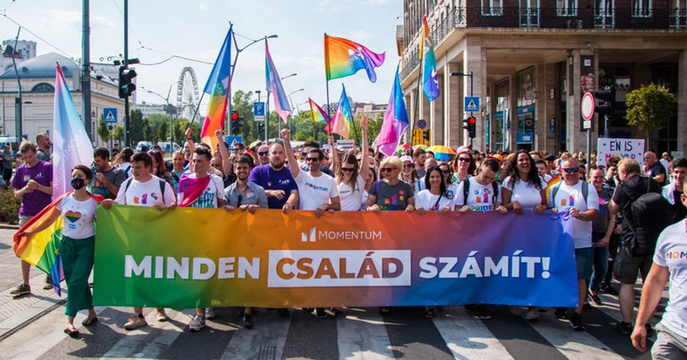 Ireland to join EU case against Hungary's anti-LGBTQ+ law. In the photo, a group of people marching at Budapest Pride, carrying a banner and waving flags.