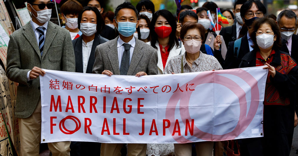 People marching for same-sex marriage in Japan, while holding a banner that reads "marriage for all Japan".