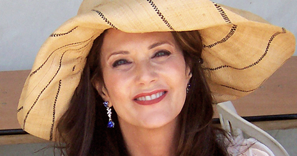 Lynda Carter smiling with a sun hat on.