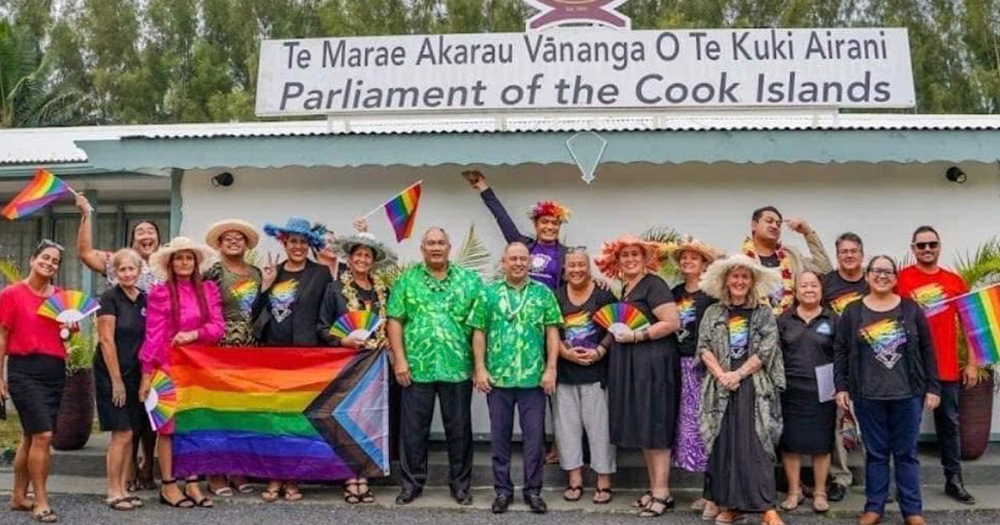 Members of Pride Cook Islands stood outside the Parliament building alongside Prime Minister Mark Brown and Government MP Tingika Elikana holding Pride flags and accessories.