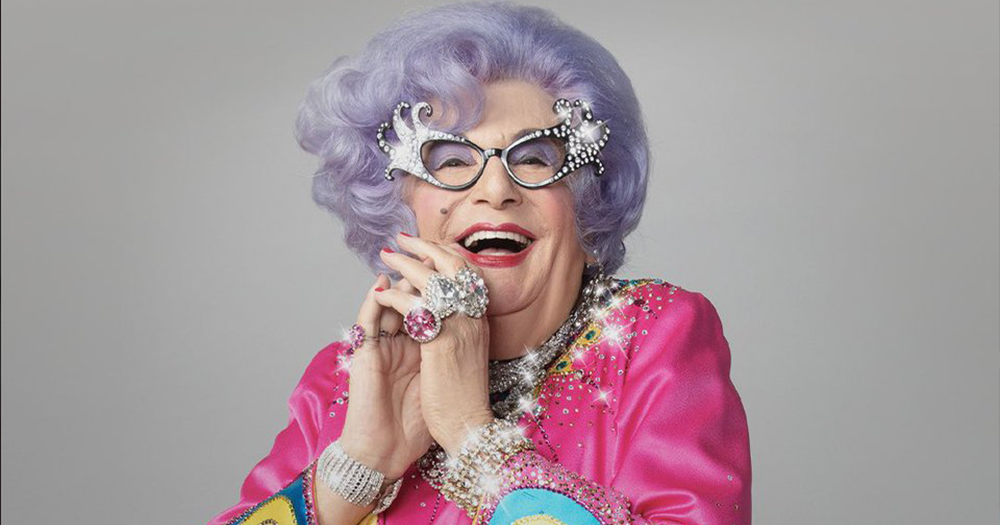 This image shows a close up of Dame Edna Everage in her signature lavender-coloured hair and glittery glasses.