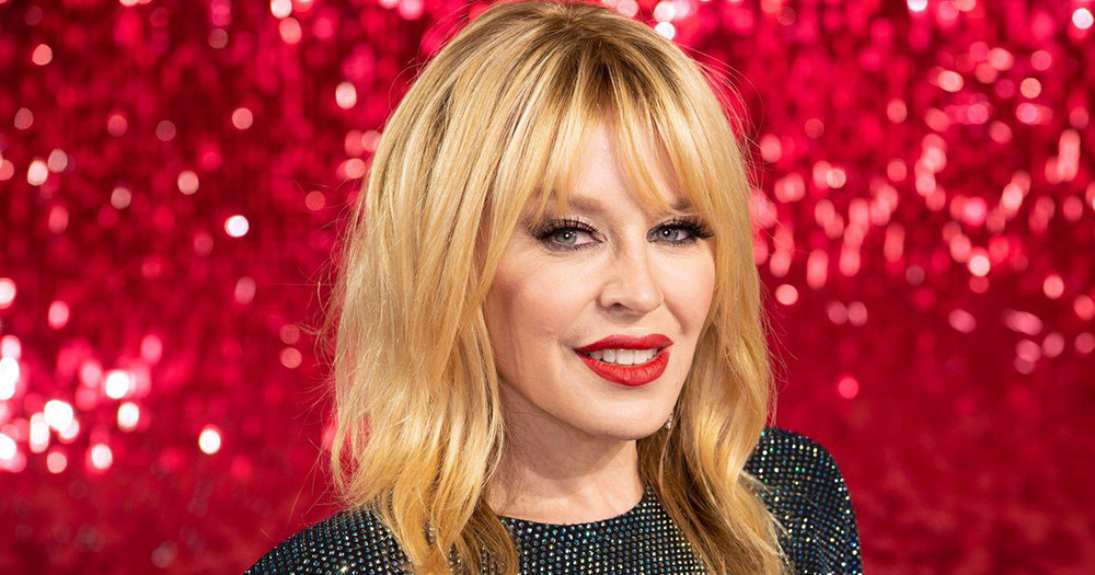 Kylie Minogue stands in front of red glitter background, she will be joining the cast of a new murder mystery Netflix series.