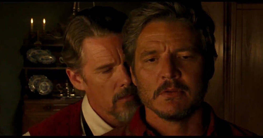 Screenshot of Pedro Pascal and Ethan Hawke star in new gay Western, 'Strange Way of Life'. In the image Ethan Hawke is whispering in Pedro Pascal's ear.