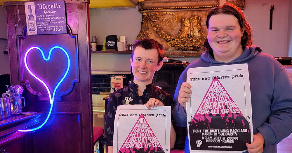Organisers Ollie Bell and Conor Tormey stand with the 2023 Trans and Intersex Pride march posters.