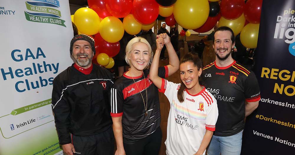 Four people pose with red and yellow ballons celebrating their one year together as a LGBTQ+ GAA club.