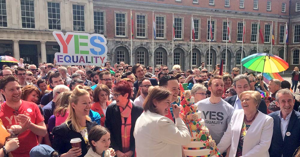 Crowd with cake and rainbow props gathers at Dublin castle to celebrate the marriage referendum in Ireland.
