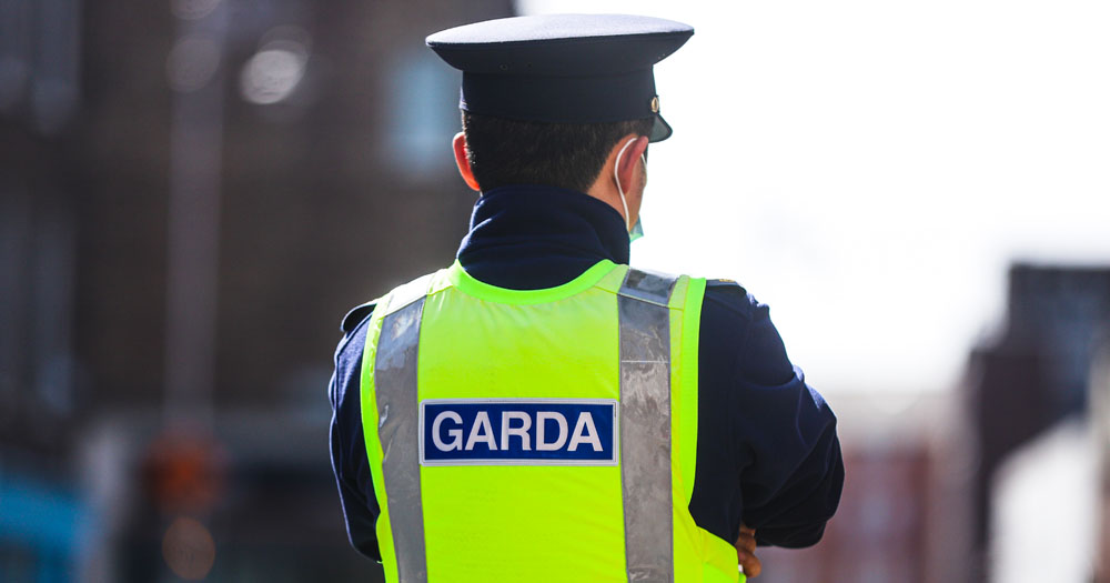 Three youths have been arrested in Navan following a brutal assault on a young man. The image shows the back of a Garda. He is wearing a navy uniform and hat and a hi-vis vest with the word 'Garda' on it.