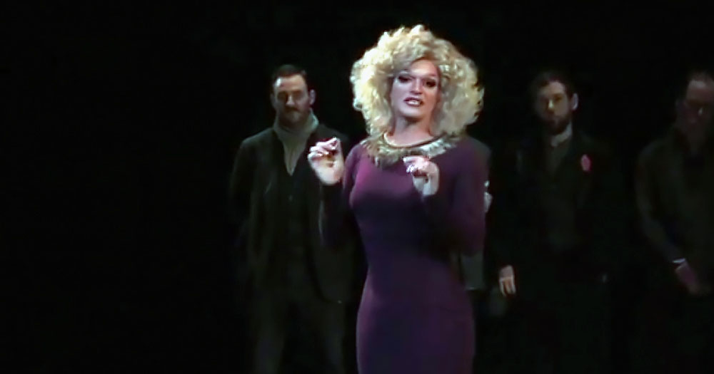 A photo of drag queen Pant Bliss on the stage of the Abbey Theatre during her Noble Call following Pantigate. The image shows Panti wearing a purple dress and a blonde curly wig.
