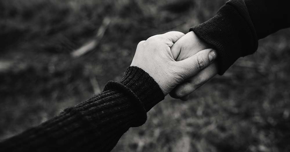 Black and white image of two holding hands symbolising a platonic partnership