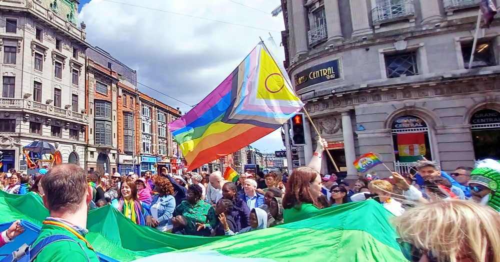 This article is about Ireland ranking 16th in the Rainbow Europe report on LGBTQ+ rights. In the photo, a crowd marching in a Pride parade in Dublin, holding the progress pride flag.