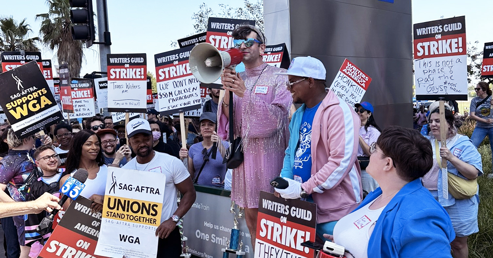 Trans writers in the US protesting with signs that read "writers guild on strike".
