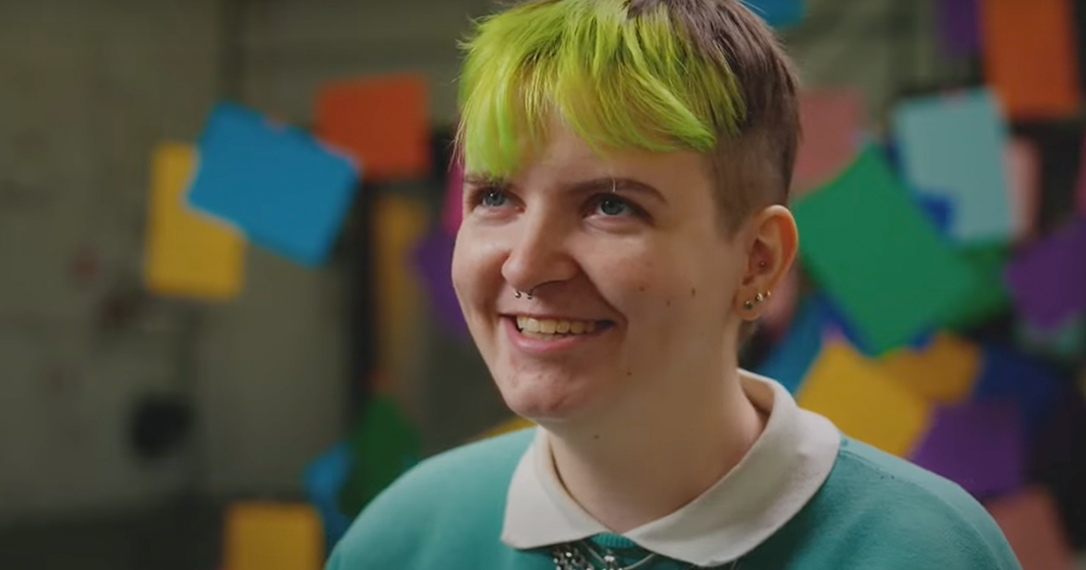 Person with green ahir smiles toward camera while talking about how queer and autistic representation is lacking in Ireland.