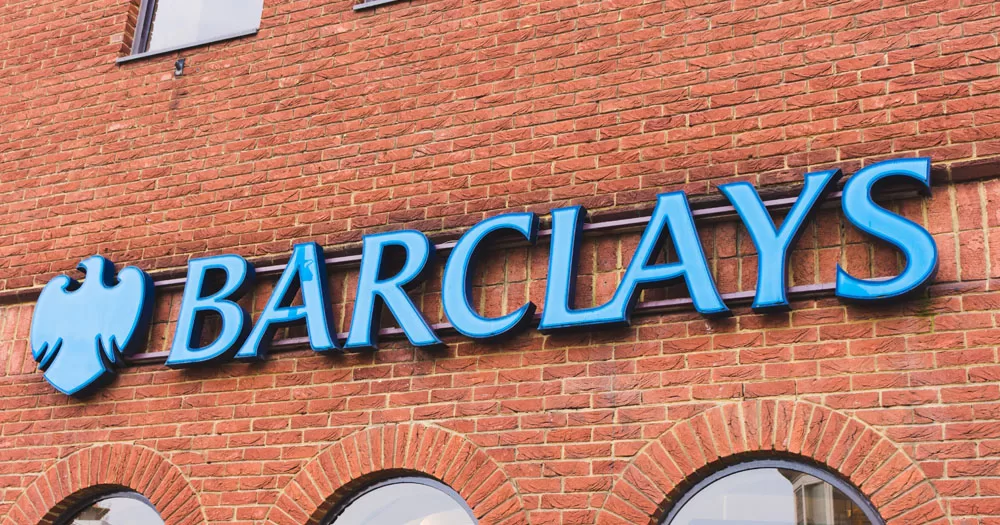 Barclays has paid out £21,500 to Christian group Core Issues Trust. The image shows the front of a Barclays bank. The building is red brick with arched windows. The Barclays' sign is blue lettering with the graphic of an eagle.