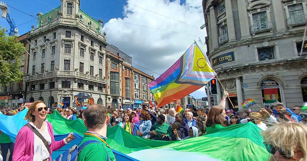 Group of people with Pride flags in Ireland, conversion therapy ban legislation is in progress.