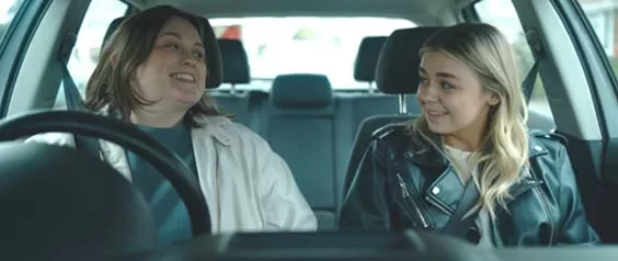two people sit in car advertising queer film premiering in July 