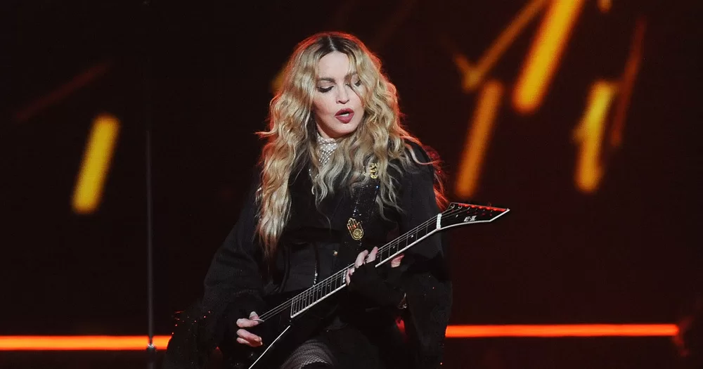 Madonna playing an electric guitar on tour in Prague.