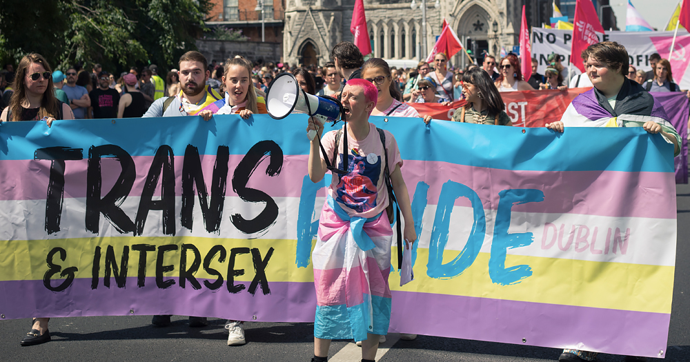 Photo take at Trans and Intersex Pride, with this year's event supported by Mother Pride Block Party, showing people marching with banners and flags in support of trans rights.