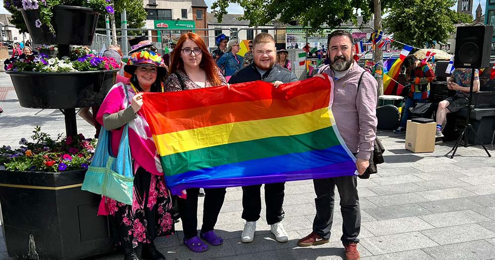 Four people stand with rainbow Pride flag in honour of the Navan Pride parade and festival.