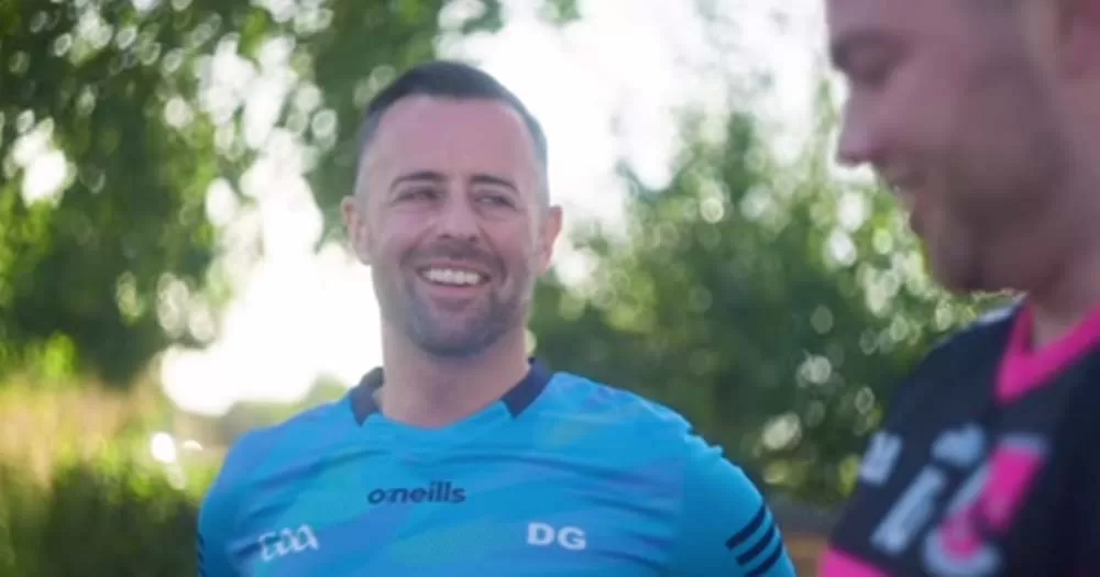 David Gough wearing blue GAA jersey smiles toward interviewer in new Irish LGBTQ+ series.