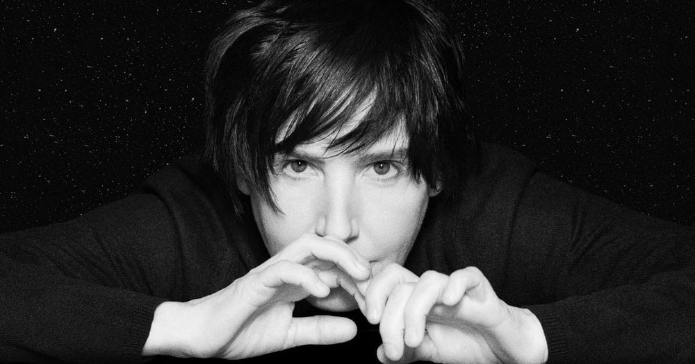 We're giving away free tickets to see Texas in concert. The image shows the band's front woman Sharleen Spiteri. It is a black and white headshot. She has her hands raised across her month.