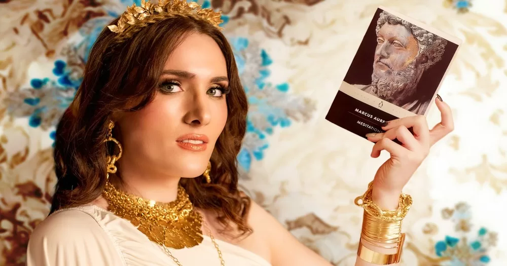 Actor Abigail Thorn dressed as a goddess holding a copy of Marcus Aurelius' "Mediations"