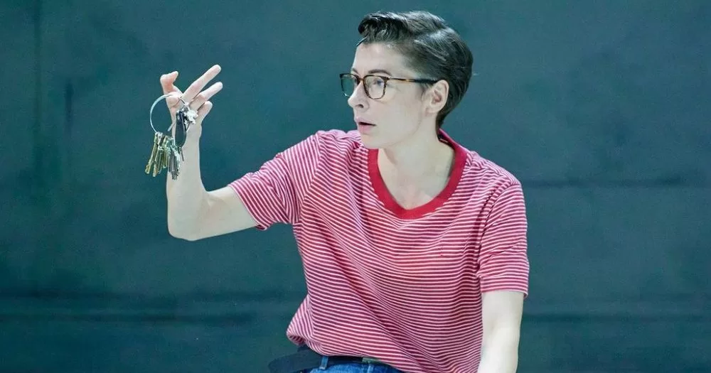 A scene from the Fun Home musical is set on stage, the main character Alison holds keys limply in her right hand. The Fun Home musical will be accompanied by the Bechdel Fest which is a series of small events highlighting the lesbian and queer history of Ireland.