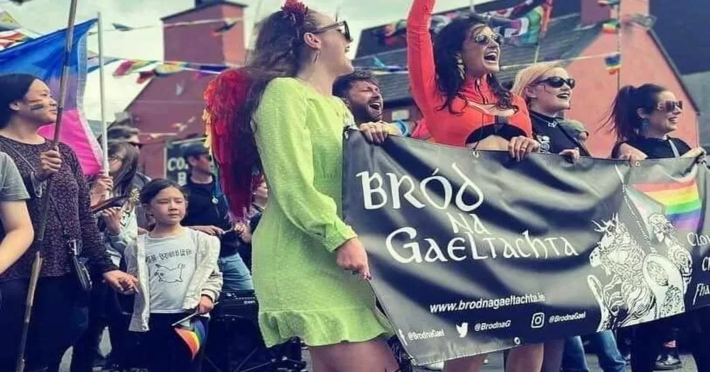 People marching in a Pride parade, holding a banner that reads "Brod na Gaeltachta"
