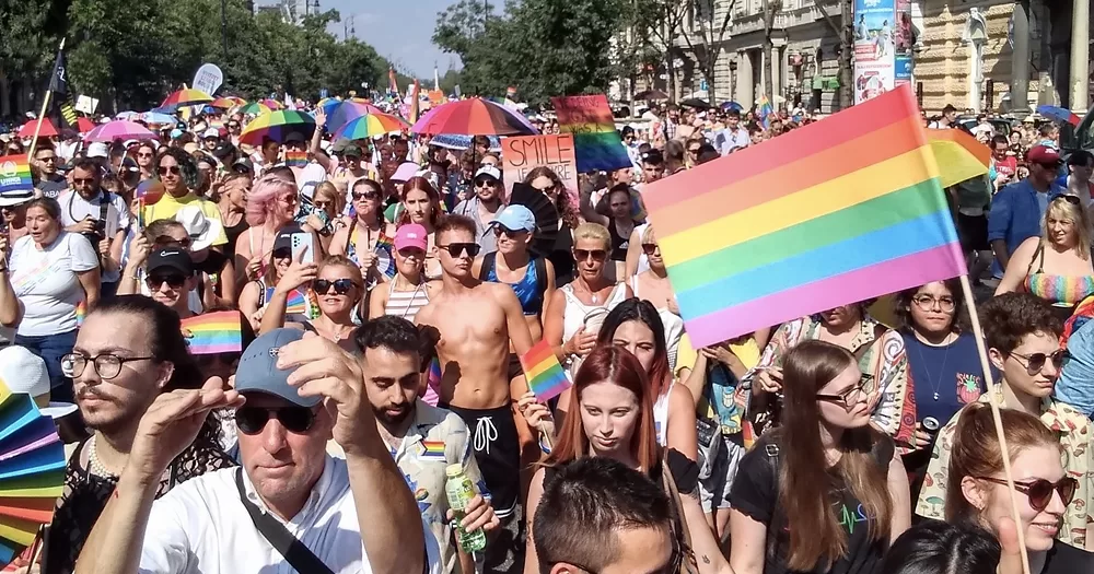 LGBTQ+ community marching at Budapest Pride, waving rainbow flags.
