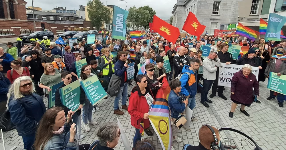 Solidarity march for Cork library staff, with people holding Pride flag and banners that read 