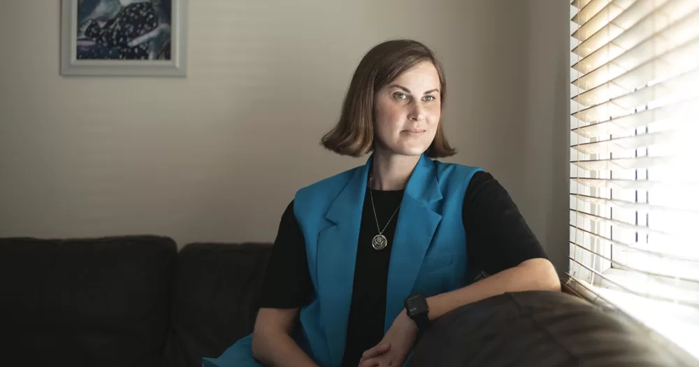 CEO of Equality for Children Ranae von Meding, wearing a blue vest on a black t-shirt, sitting on a sofa.